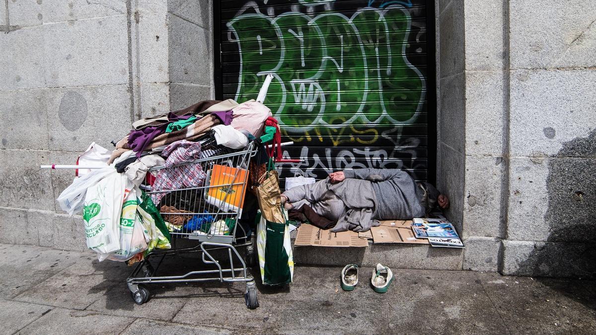 Una persona sintecho duerme en una calle.