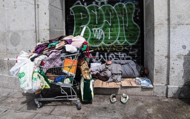 Una persona sintecho duerme en una calle.