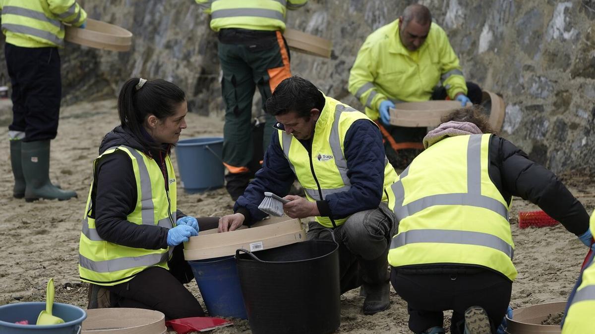 Operarios retiran los pellets o bolitas para fabricar plástico que aparecen en las playas de Asturias, tras la caída de un contenedor de un barco el pasado diciembre, esta mañana enla playa asturiana del Aguilar.