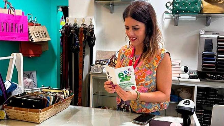 Una dependienta de un comercio de Laudio consultando el folleto de la campaña