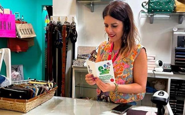 Una dependienta de un comercio de Laudio consultando el folleto de la campaña