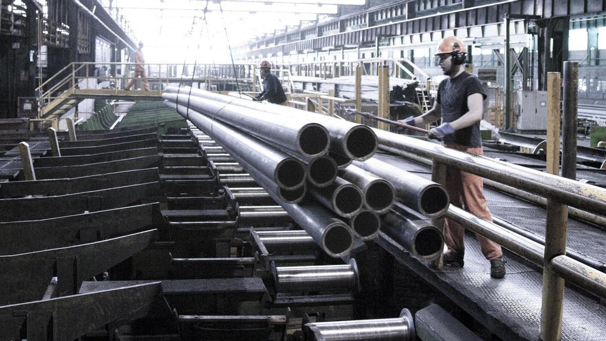 Trabajadores manipulando tubos de acero.
