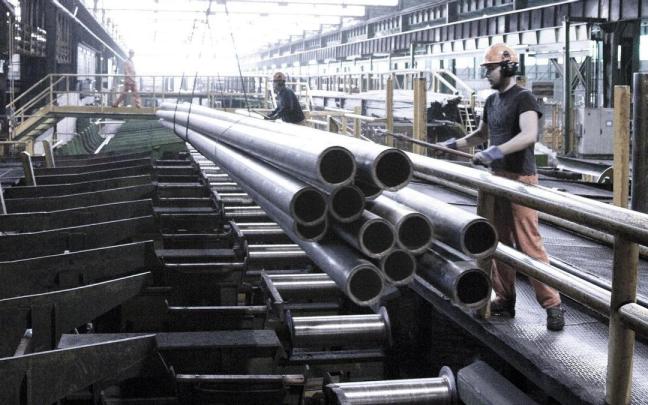 Trabajadores manipulando tubos de acero.