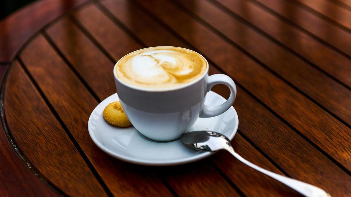 Taza de café con una cucharilla y una galleta
