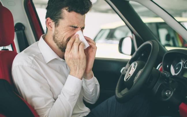 Un hombre se suena la nariz dentro del coche.