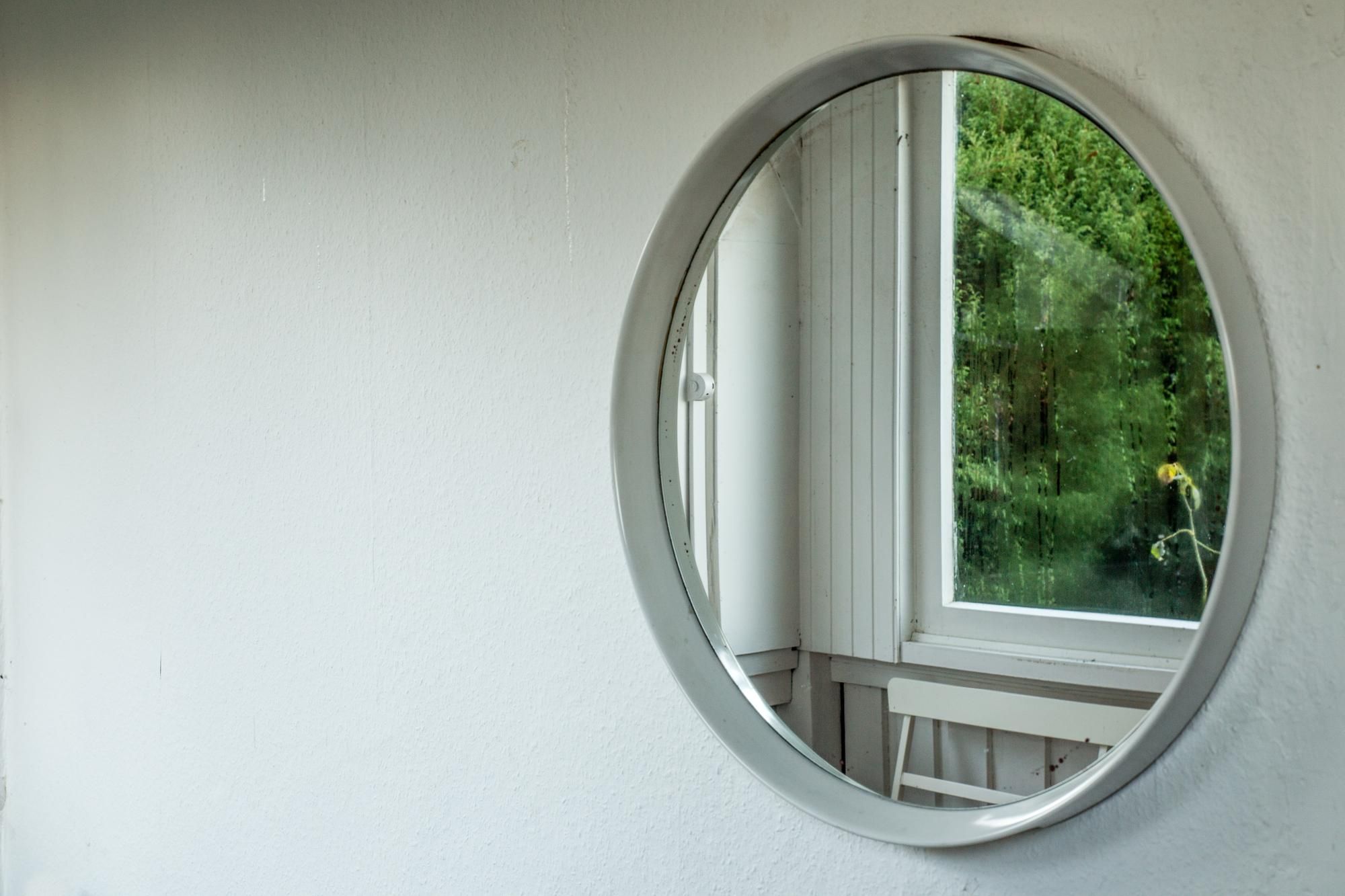 Un espejo refleja la arboleda que se ve desde la ventana.