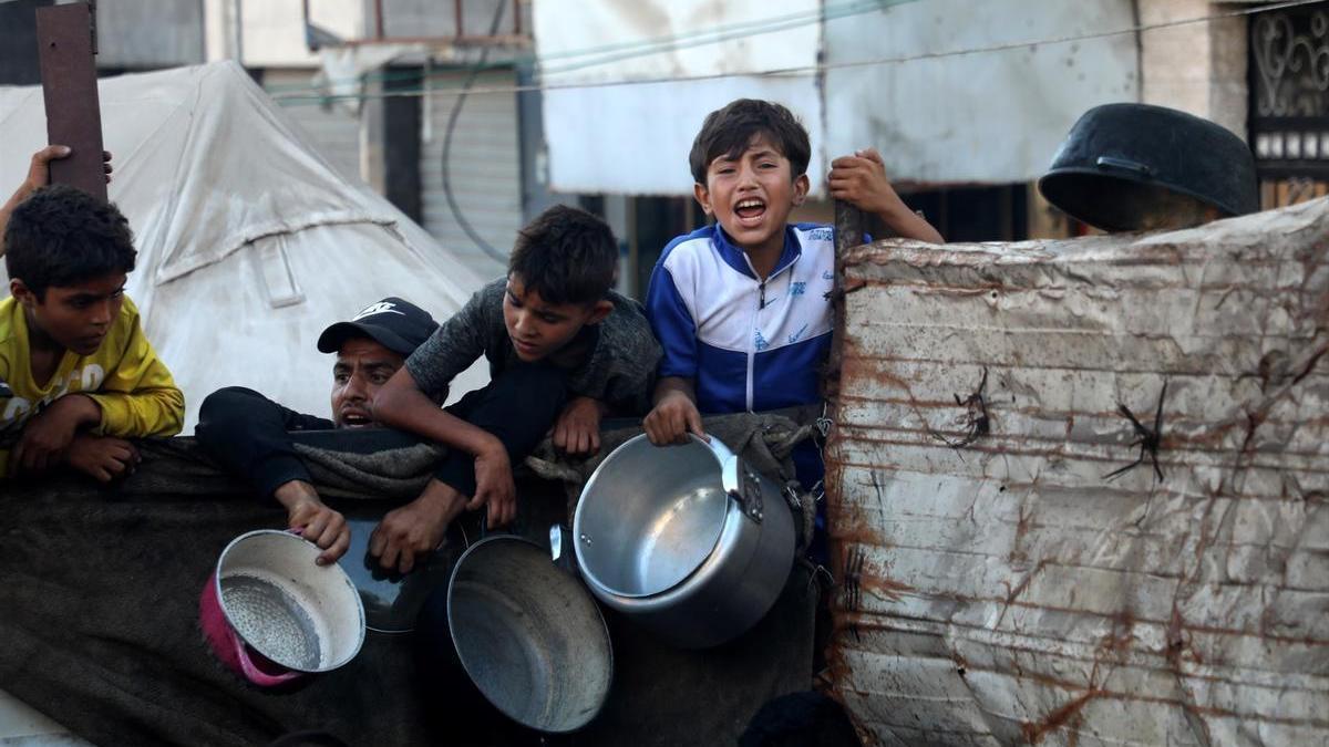 Ciudadanos gazatíes, entre ellos varios niños, esperan para recibir alimentos en la capital de la Franja.
