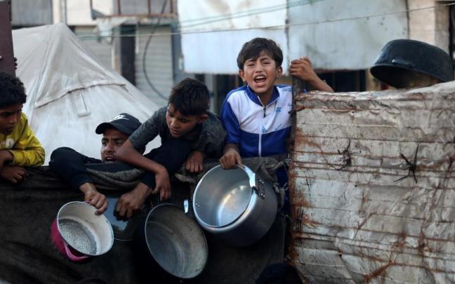 Ciudadanos gazatíes, entre ellos varios niños, esperan para recibir alimentos en la capital de la Franja.
