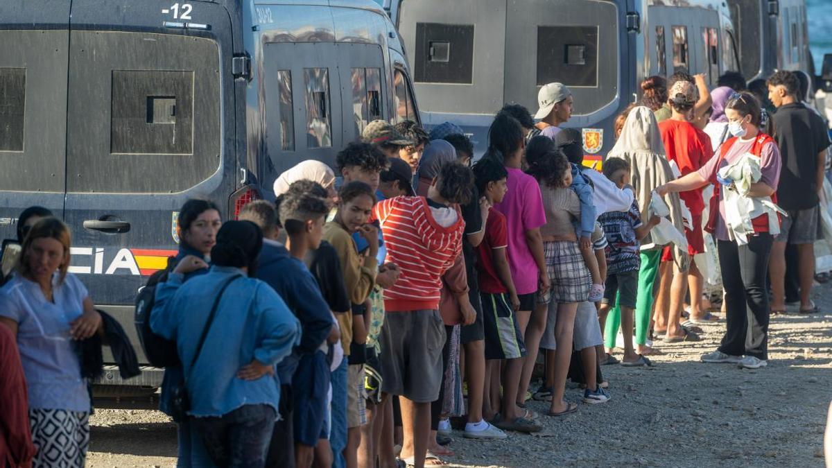 Miembros de la Cruz Roja reparten comida a los inmigrantes en una playa de Ceuta.