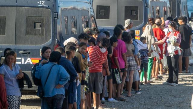 Miembros de la Cruz Roja reparten comida a los inmigrantes en una playa de Ceuta.