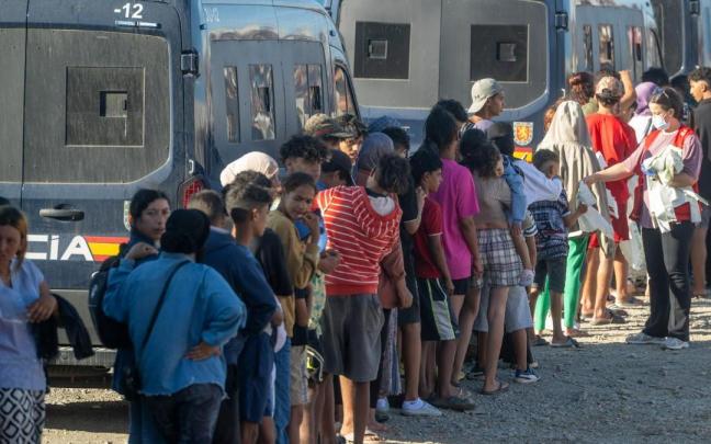 Miembros de la Cruz Roja reparten comida a los inmigrantes en una playa de Ceuta.