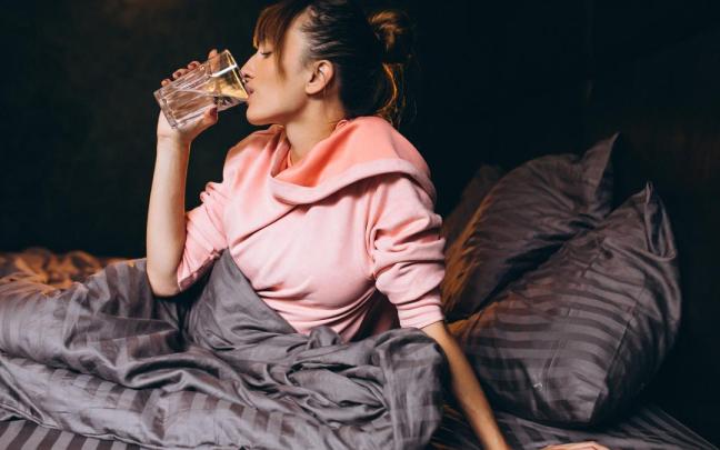 Una mujer bebe agua en la cama.