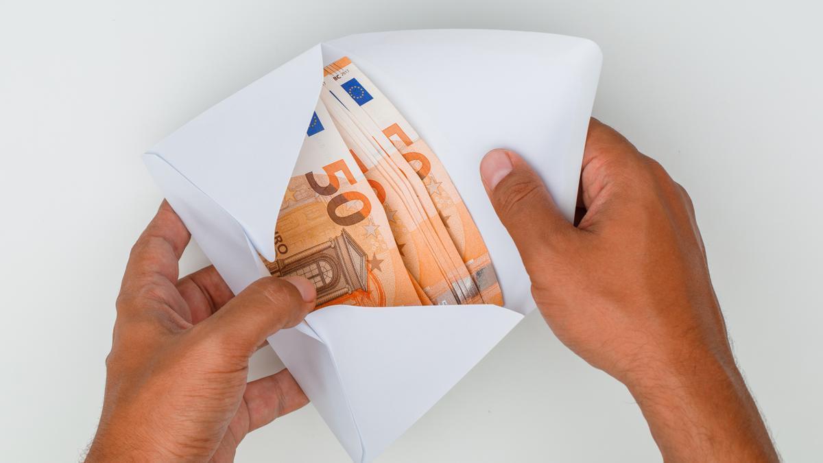 Una persona abre un sobre lleno de billetes de 50 euros