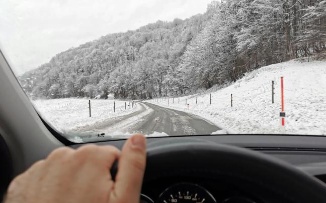Una persona conduce en una carretera con nieve.