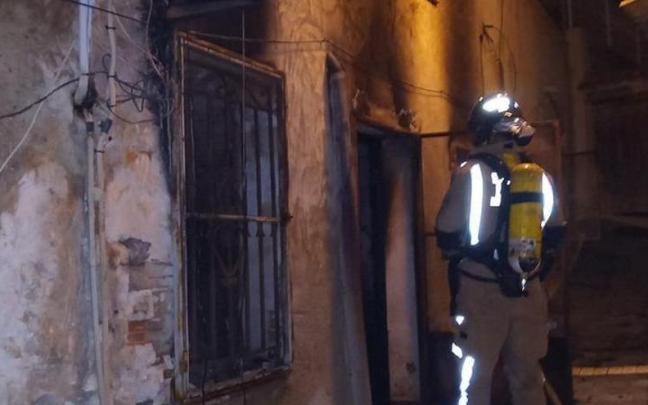 Un bombero inspeccionando la casa incendiada.