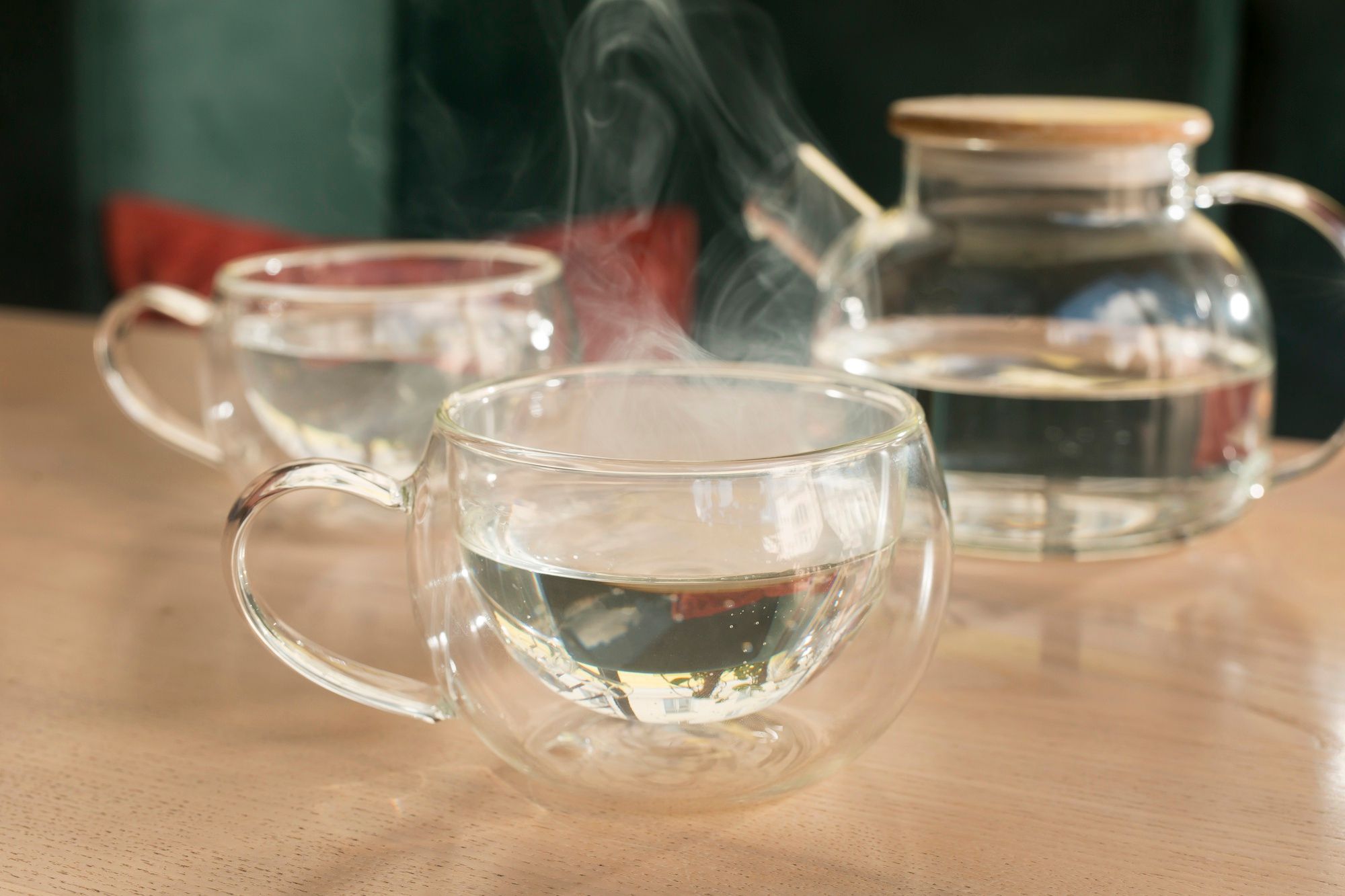 Una jarra y dos humeantes tazas con agua caliente.