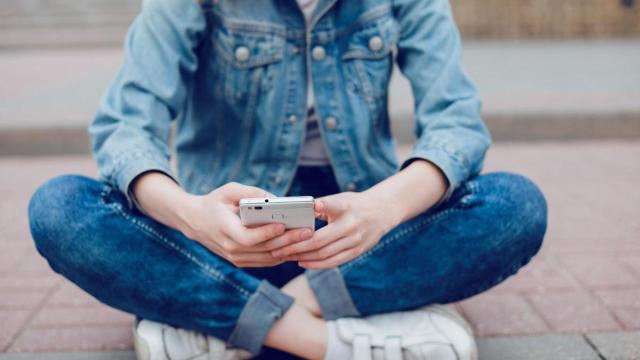 Una adolescente utiliza un teléfono móvil.
