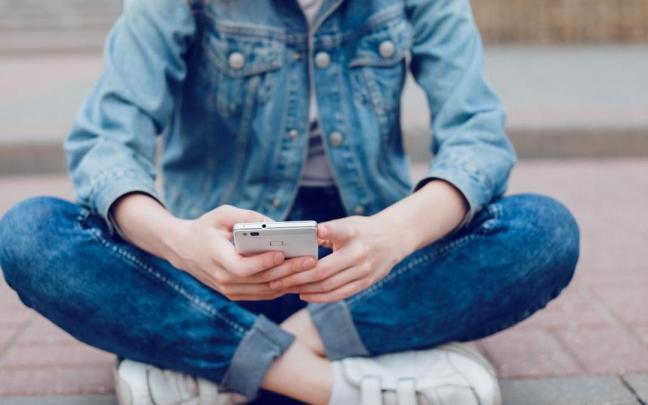 Una adolescente utiliza un teléfono móvil.