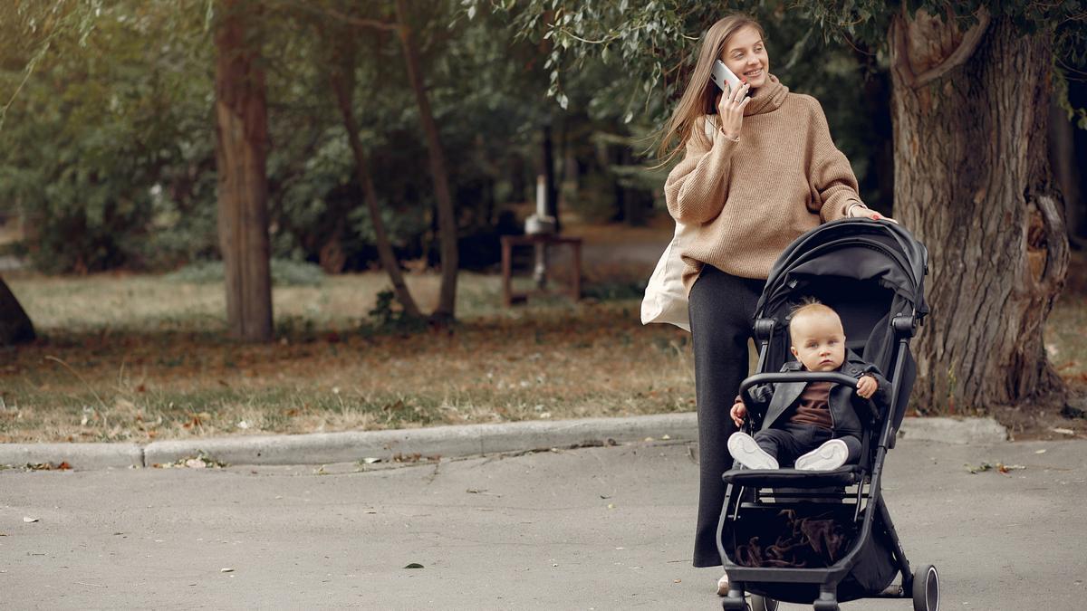 Una mujer pasea con su hijo por un parque.