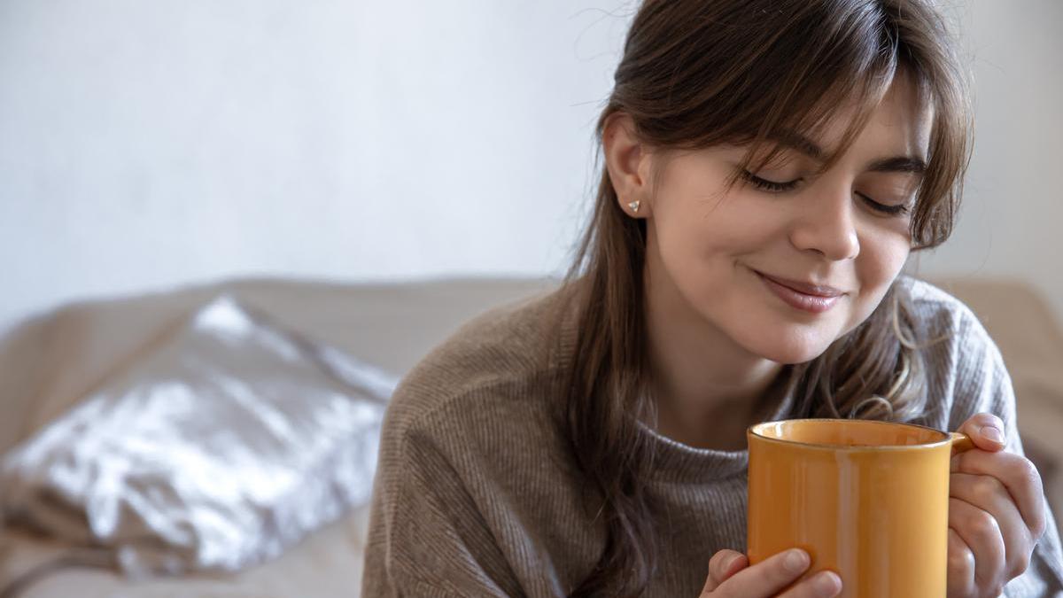 Joven sonriendo con una taza de chocolate caliente en la mano