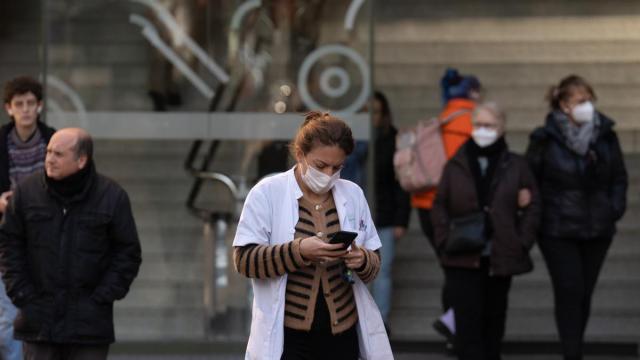 Varias personas con mascarilla en el acceso a un hospital.