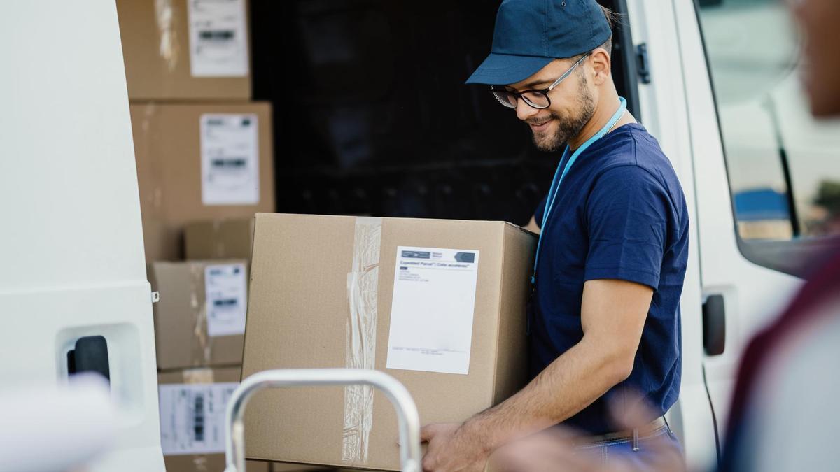 Un repartidor de paquetería descarga cajas de una furgoneta.
