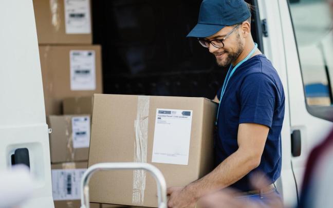 Un repartidor de paquetería descarga cajas de una furgoneta.