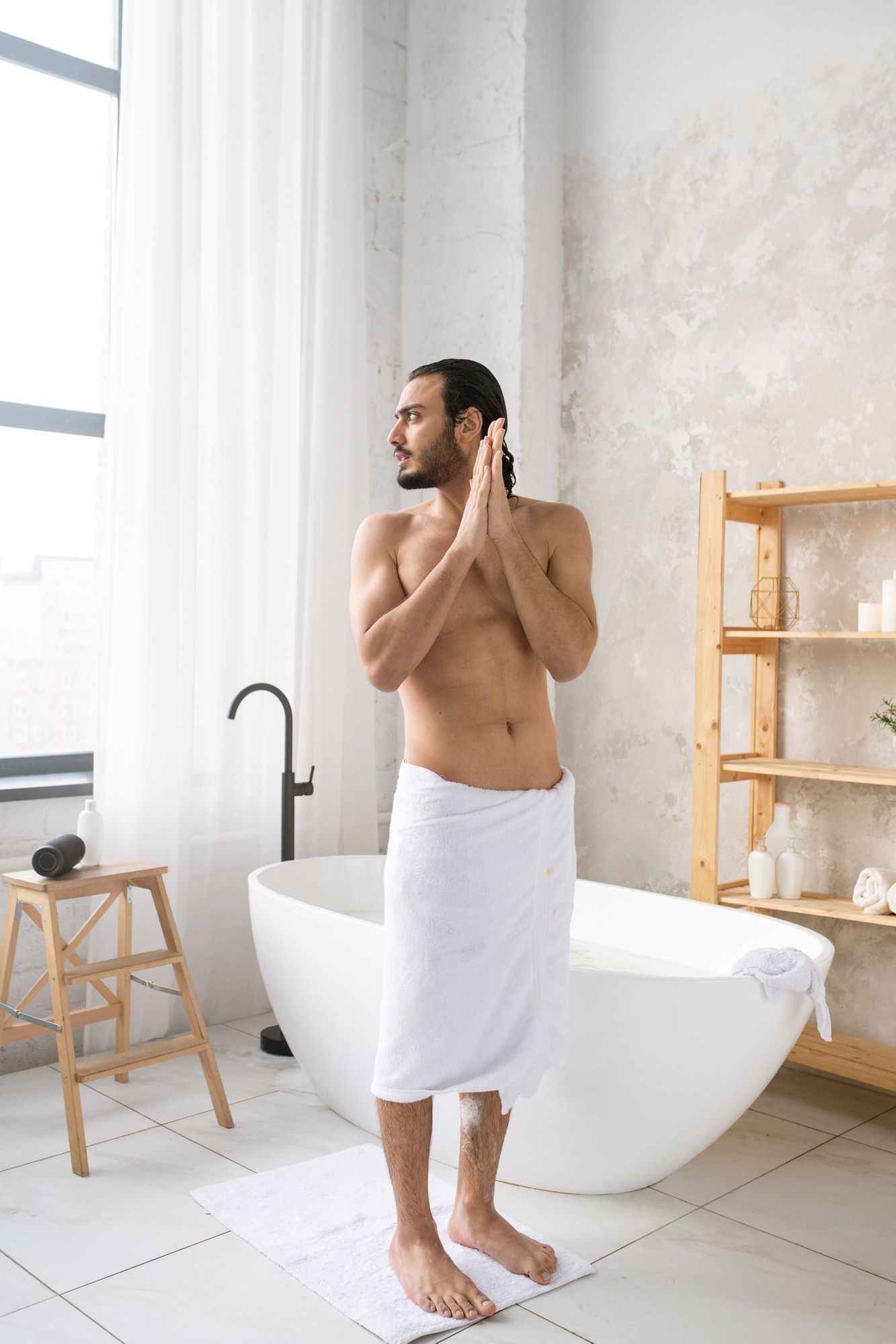 Un hombre va a aplicarse crema hidratante después de tomar un baño.