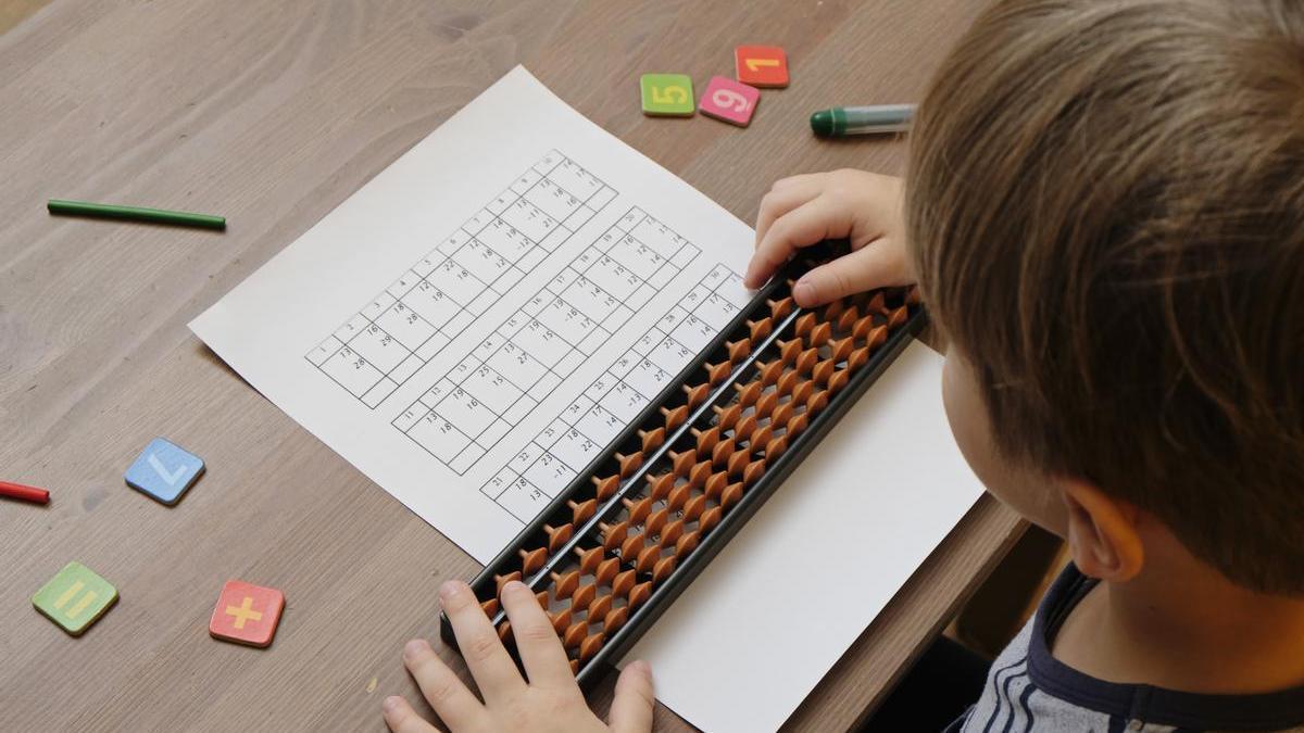 Un niño trabajando conceptos matemáticos con ábacos.