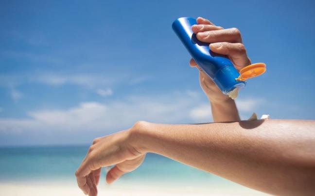 Una mujer se aplica protección solar en la playa