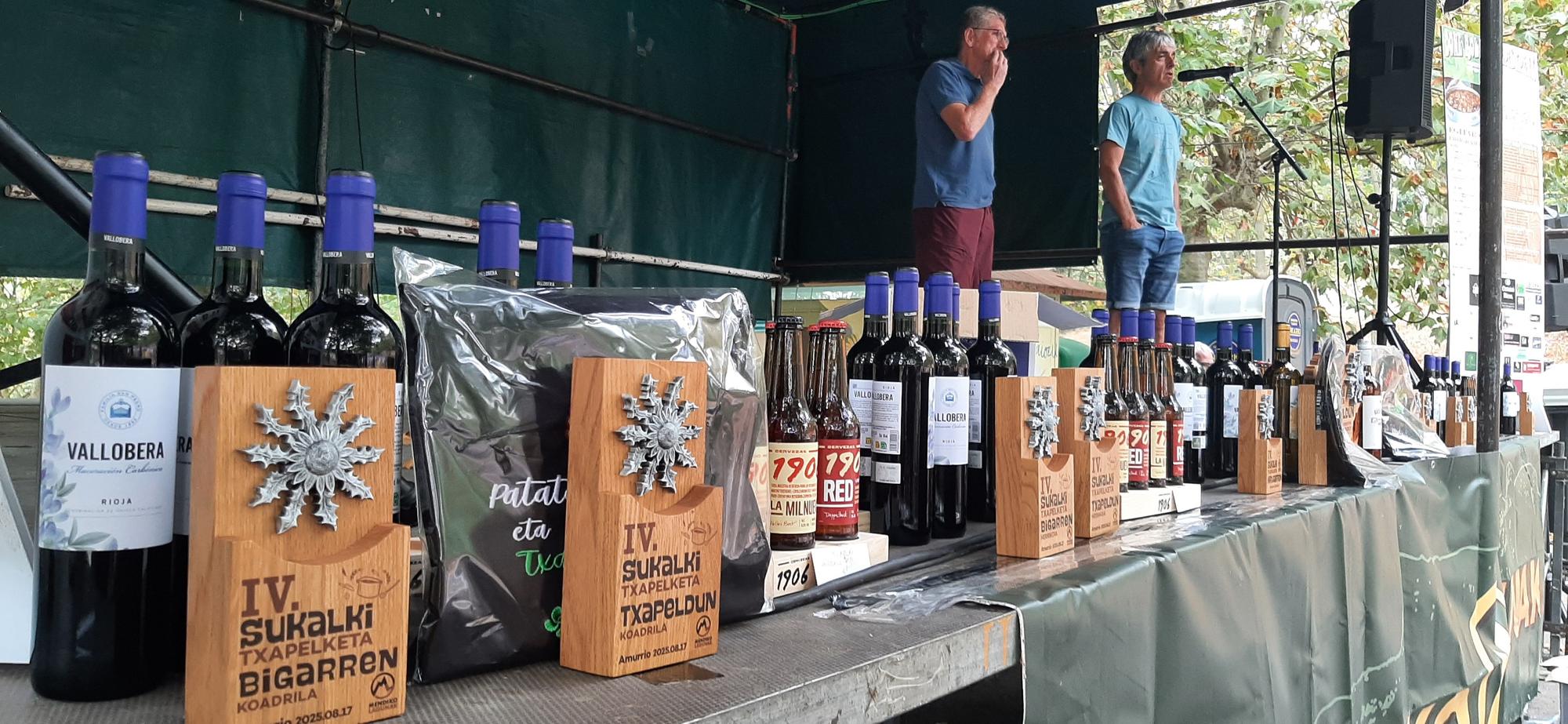 Los bertsolaris Juanjo Respaldiza y Serapio López actuando con parte de los trofeos entregados a sus pies