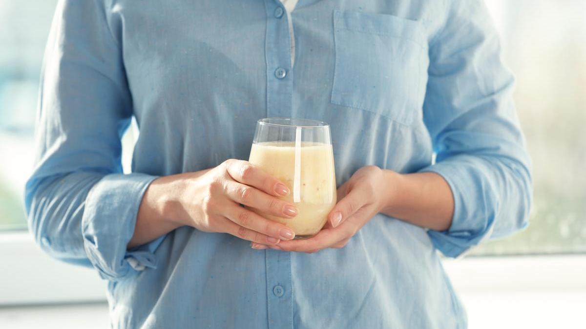 Mujer sostiene un vaso con bebida de soja.