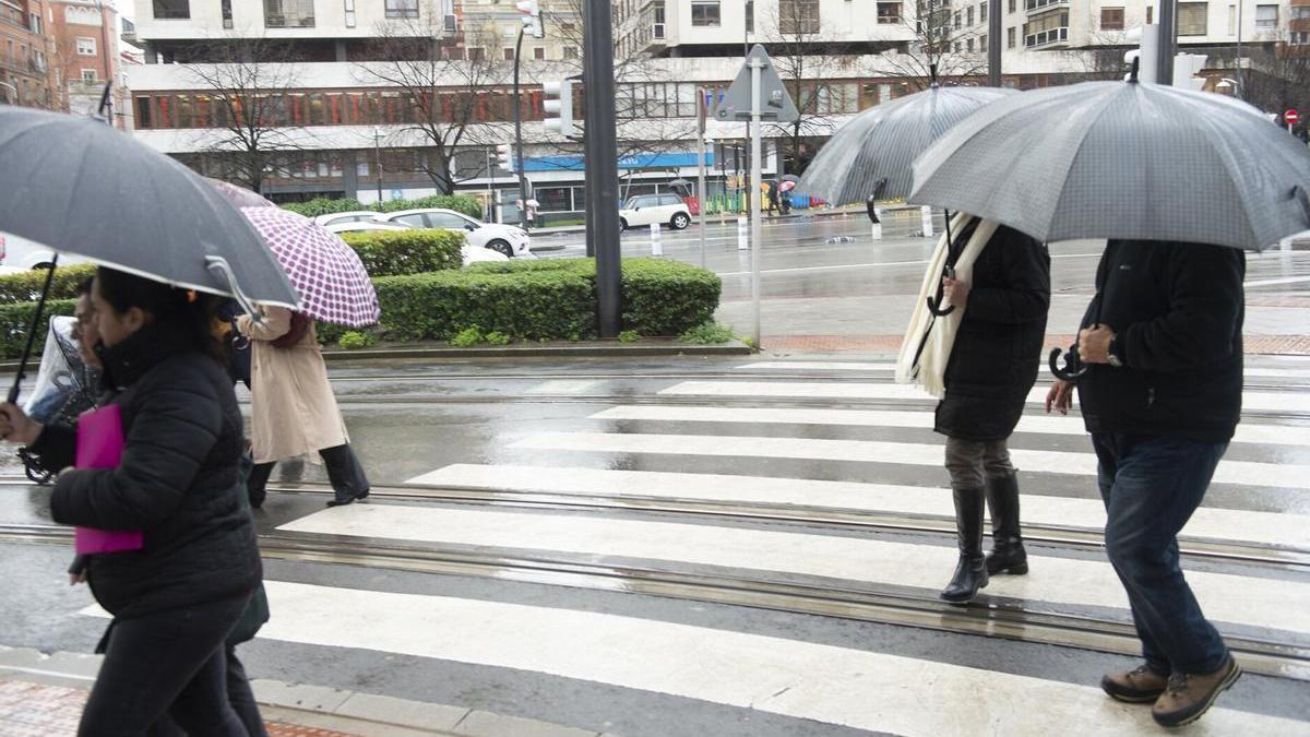 Varias personas se resguardan de la lluvia bajo sus paraguas.