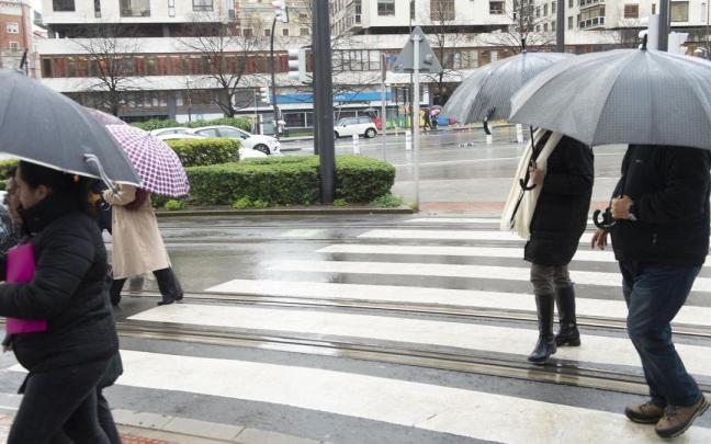 Varias personas se resguardan de la lluvia bajo sus paraguas.