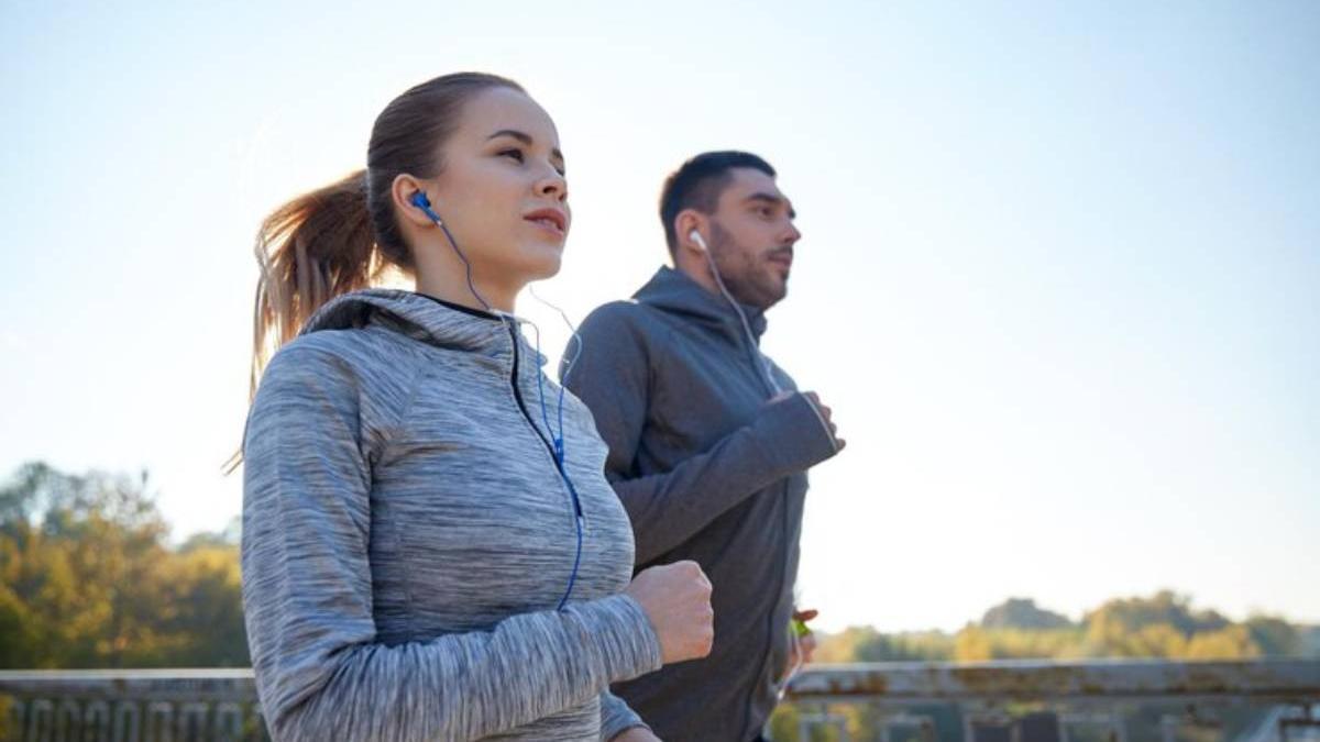 Pareja sale a correr al aire libre por la tarde.
