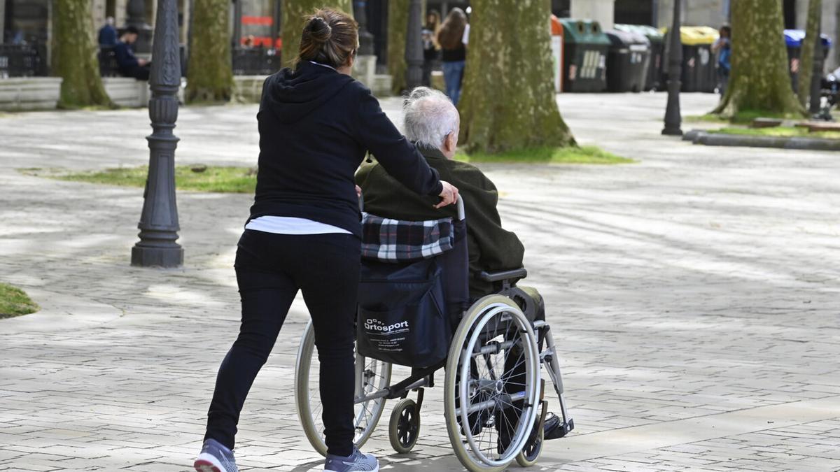 Una mujer empuja la silla de ruedas de un anciano