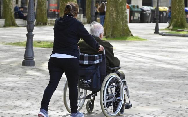 Una mujer empuja la silla de ruedas de un anciano