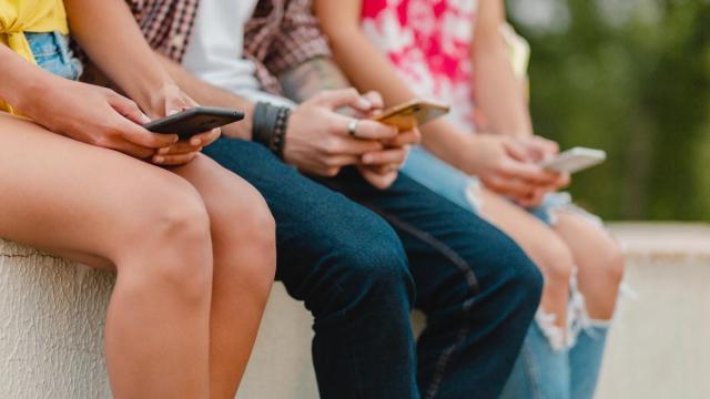 Tres menores con sus teléfonos móviles.