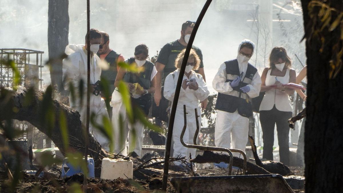 Agentes y personal forense inspeccionan las chabolas calcinadas tras el incendio registrado en el asentamiento de La Sevillana, en Lucena del Puerto.