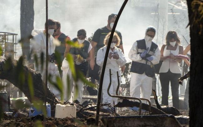 Agentes y personal forense inspeccionan las chabolas calcinadas tras el incendio registrado en el asentamiento de La Sevillana, en Lucena del Puerto.