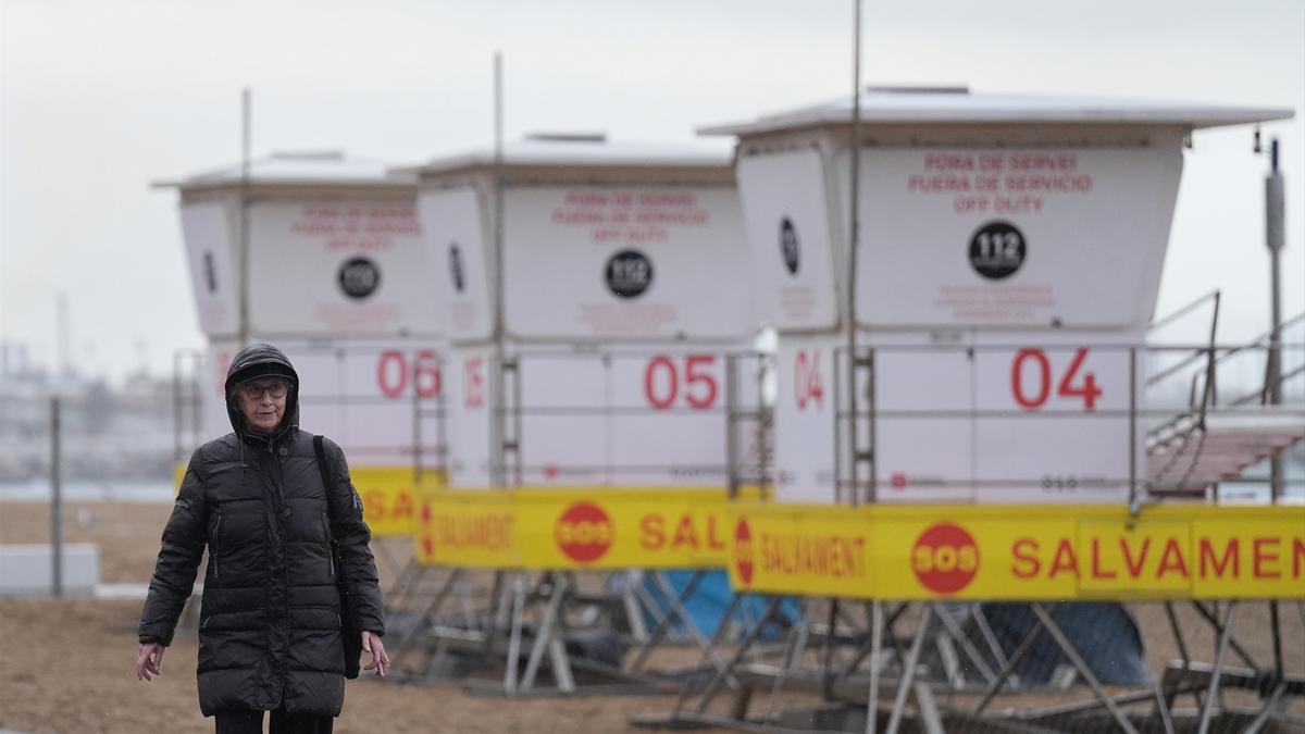 Vecinos de Barcelona pasean bajo la lluvia en la playa de la Barceloneta durante el temporal, a 19 de enero de 2026.