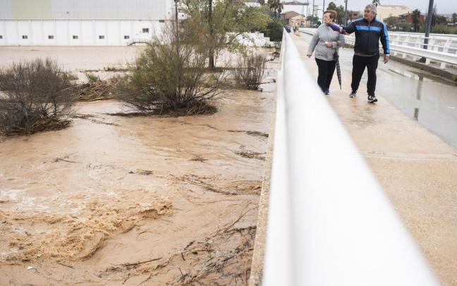 Varias personas observan la crecida del río Magro.