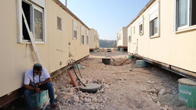 Un colono judío está sentado junto a unas casas prefabricadas en el asentamiento de Ganim, en Cisjordania.