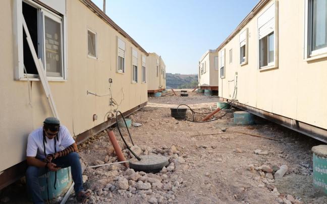 Un colono judío está sentado junto a unas casas prefabricadas en el asentamiento de Ganim, en Cisjordania.