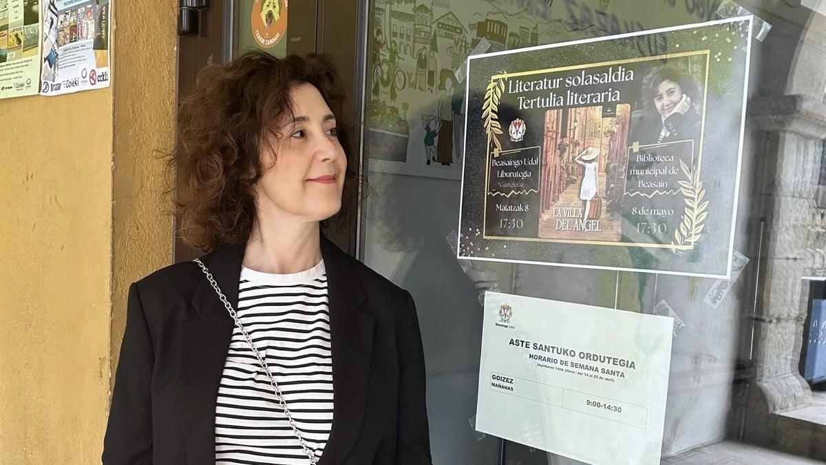 La escritora beasaindarra, Mariluz Cabezas, junto al cartel que anuncia la tertulia en la que participará