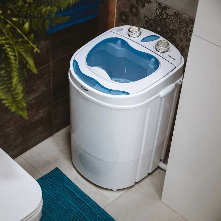 Mini lavadora colocada en un rincón del baño.