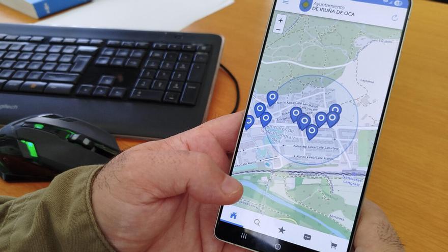 Una persona muestra en su móvil la APP KIcerca de Iruña de Oca