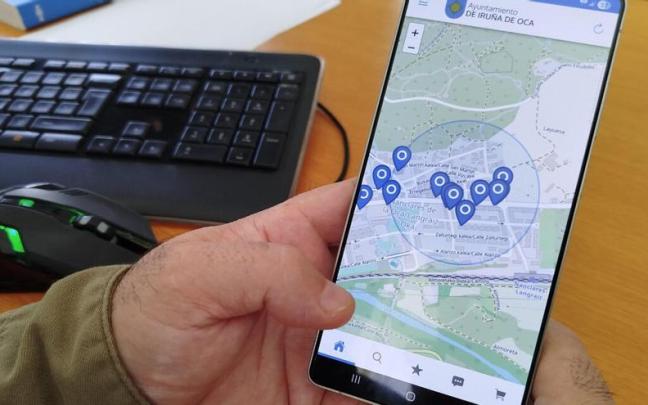 Una persona muestra en su móvil la APP KIcerca de Iruña de Oca