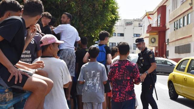 Un grupo de menores espera para ser filiado en una comisaría de la Policía Nacional en Ceuta.