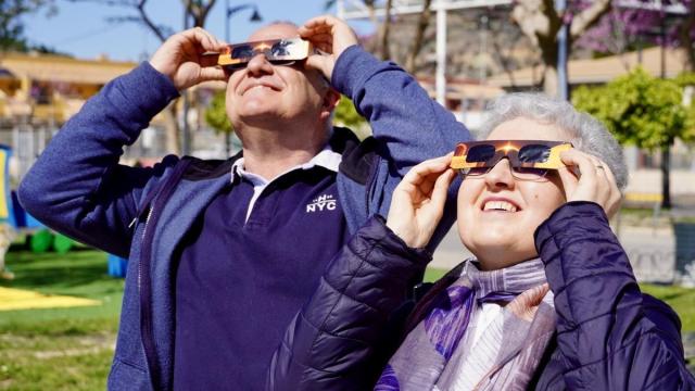 Una pareja contempla un eclipse con una gafas especiales para ello.